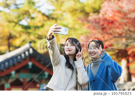 友達と秋の旅行に出かけてスマホで写真を撮る女性 101795025