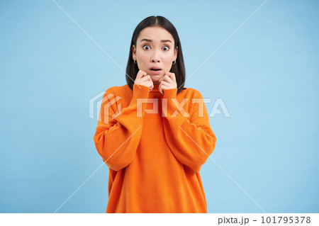 Korean woman with shocked, scared face expression, watches horror, looks terrified, startled by smth scary, stands over blue background Korean woman with shocked, scared face expression, watches horror, looks terrified, startled by smth scary, stands over blue background 101795378