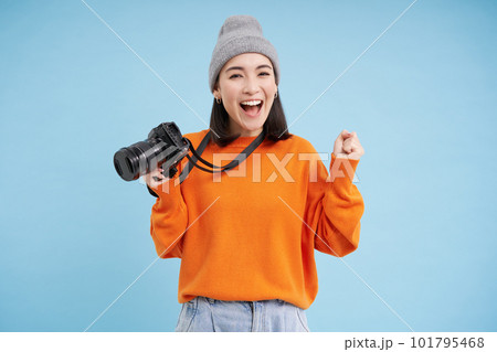 Stylish asian girl with digital camera, taking pictures. Woman photographer smiling, standing over blue background Stylish asian girl with digital camera, taking pictures. Woman photographer smiling, standing over blue background 101795468