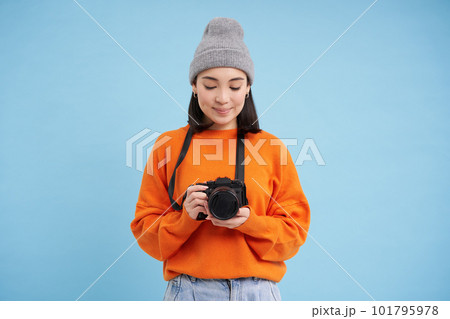 Passionate asian girl photographer, taking pictures on her digital camera, capturing moments outdoors, shooting photos, blue background Passionate asian girl photographer, taking pictures on her digital camera, capturing moments outdoors, shooting photos, blue background 101795978
