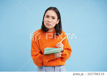 Education and students. Happy asian woman, holding notebooks and laughing, smiling at camera, enjoys going to University or College, blue background Education and students. Happy asian woman, holding notebooks and laughing, smiling at camera, enjoys going to University or College, blue background 101796519