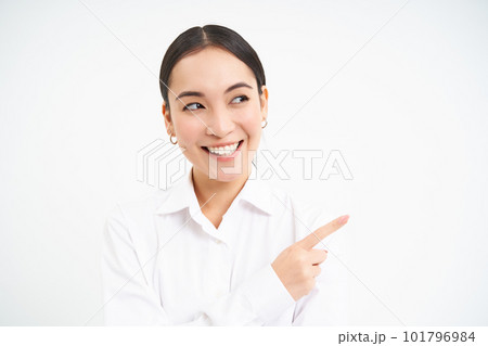 Successful korean businesswoman, pointing finger right, showing advertisement on banner, standing over white background Successful korean businesswoman, pointing finger right, showing advertisement on banner, standing over white background 101796984
