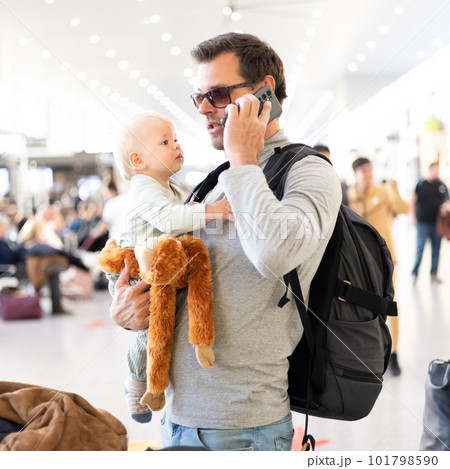 Father traveling with child, holding his infant baby boy at airport terminal waiting to board a plane. Travel with kids concept Father traveling with child, holding his infant baby boy at airport terminal waiting to board a plane. Travel with kids concept 101798590