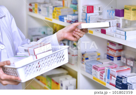 Pharmacist chemist woman standing refills the shelves with new stocks in pharmacy drugstore Pharmacist chemist woman standing refills the shelves with new stocks in pharmacy drugstore 101802359