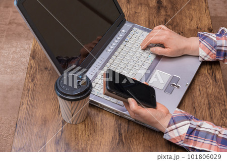 【ノートパソコンとスマホを操作する女性の手元】 101806029