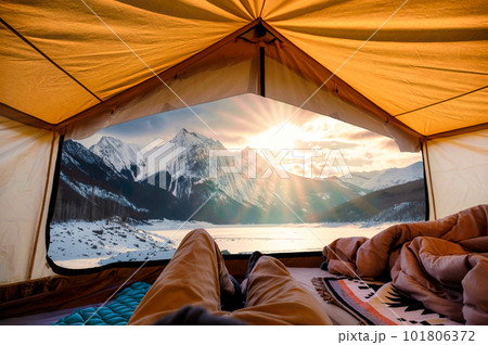 Traveler man relaxing inside a yellow tent with sunrise over Medicine Lake in winter at Jasper national park 101806372