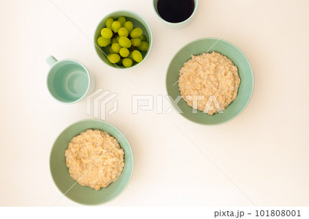 Top view of morning meal on white background. Oatmeal with cup of coffee. morning porrige with grape 101808001
