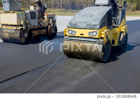 Worker operating vibratory road roller compactor process machine laying new asphalt on construction site Worker operating vibratory road roller compactor process machine laying new asphalt on construction site 101808948
