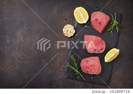 Seafood. Raw juicy tuna steaks with spices and rosemary on a stone table. View from above. Copy space. Seafood. Raw juicy tuna steaks with spices and rosemary on a stone table. View from above. Copy space. 101809719