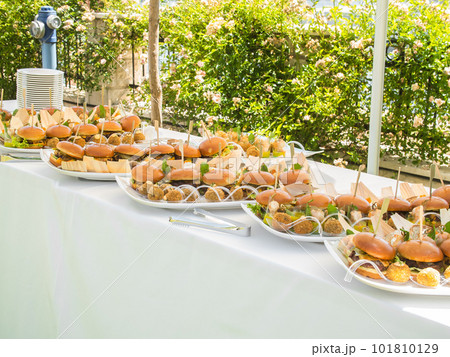 Banquet table with snacks food on plates hamburger party dinner table - buffet table after wedding ceremony Banquet table with snacks food on plates hamburger party dinner table - buffet table after wedding ceremony 101810129