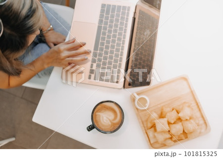 Above view of girl working on laptop with coffee and desserts in the cafe. Above view of girl working on laptop with coffee and desserts in the cafe. 101815325