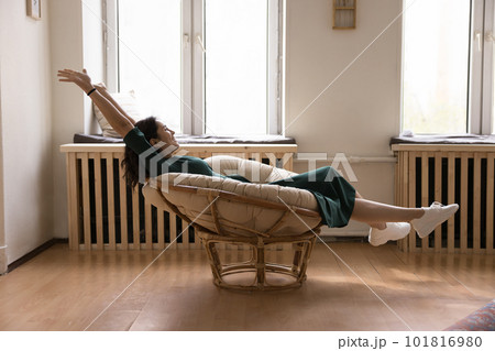 Happy young woman relaxing seated in modern chair Happy young woman relaxing seated in modern chair 101816980