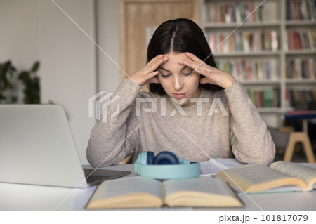 Student girl sit with textbooks learns home tasks looking tired 101817079