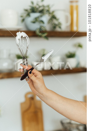 A woman cook holds a whisk and a spatula in her hand on the background of the kitchen A woman cook holds a whisk and a spatula in her hand on the background of the kitchen 101818810