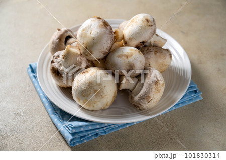 Raw champignon mushrooms in a plate. Fresh vegetables for cooking. 101830314