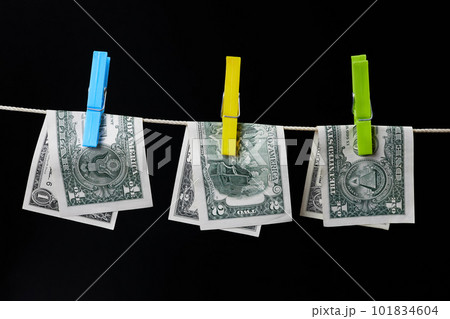 One and two dollar banknotes fastened with clothespins are dried on clotheslines on a dark background One and two dollar banknotes fastened with clothespins are dried on clotheslines on a dark background 101834604