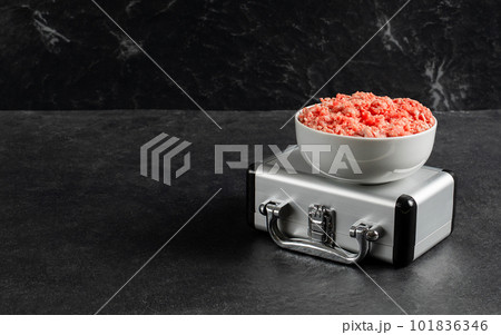 Plate with fresh ground beef, silver suitcase on a gray black background, space for text, stock photo Plate with fresh ground beef, silver suitcase on a gray black background, space for text, stock photo 101836346