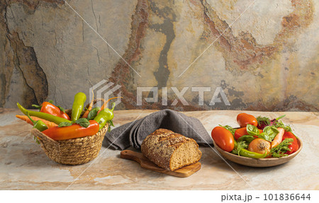 Traditional wooden plate with fresh seasonal vegetables: green pepper, tomato, onion, carrot, cucumber, basil, dill; bread, textile on brown vintage background, top view, stock photo	 101836644