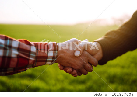 Handshake two farmer on the background of a wheat field at sunset. The concept of the agricultural. Handshake two farmer on the background of a wheat field at sunset. The concept of the agricultural. 101837005