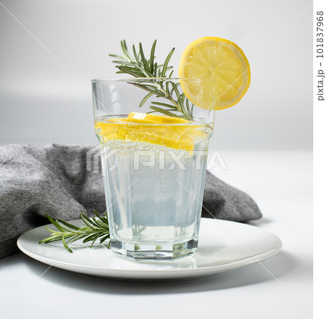 Glass with fresh lemon water or homemade lemonade and rosemary on white background, stock photo	 101837968