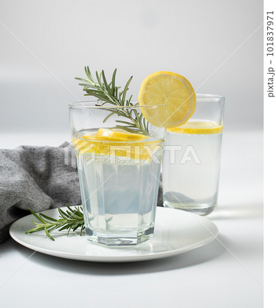 Glass with fresh lemon water or homemade lemonade and rosemary on white background, stock photo Glass with fresh lemon water or homemade lemonade and rosemary on white background, stock photo 101837971