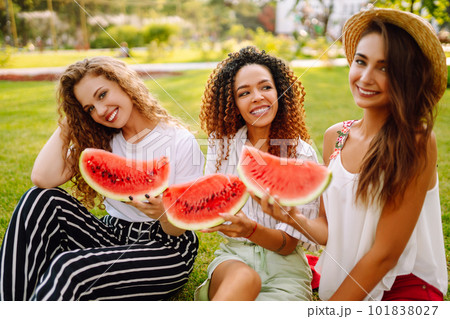 Cheerful happy friends camping on the grass, eating watermelon, laughing. 101838027