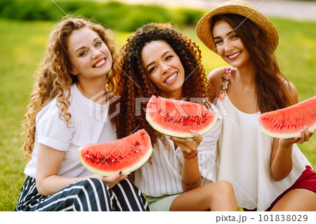 Three young woman have fun together and eating watermelon in hot summer day. 101838029