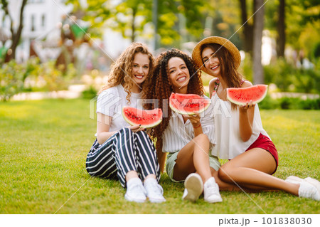Three young woman have fun together and eating watermelon in hot summer day. 101838030