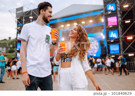 Young and cheerful couple at a music festival. People drinking beer and having fun. Youth, party. Young and cheerful couple at a music festival. People drinking beer and having fun. Youth, party. 101840629