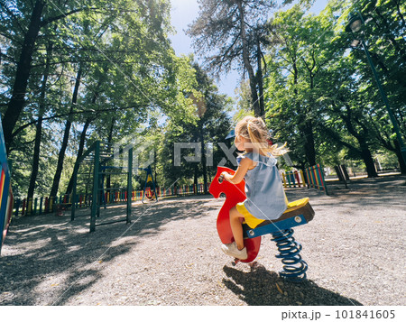 Little girl swinging on a swing-spring in the playground Little girl swinging on a swing-spring in the playground 101841605