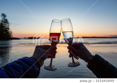 Man and Woman Cheers with Champagne Flute Glasses on the Beach at Sunset Man and Woman Cheers with Champagne Flute Glasses on the Beach at Sunset 101843849
