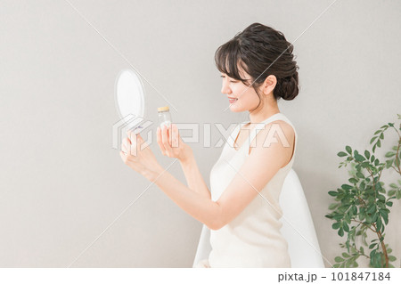 鏡を見ながら薬・サプリメントの瓶を持つ笑顔のアジア人女性 101847184