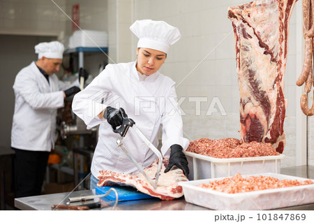 Young woman butcher sawing beef ribs 101847869