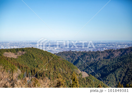 【日本】小仏城山の山頂から望む山並み越しに見える首都圏の街並みと冬晴れの青空 101849381
