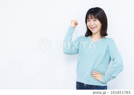 白い背景の前で笑顔でガッツポーズをしている30代の女性 101851765
