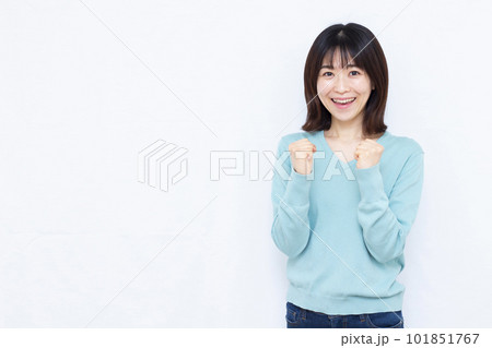 白い背景の前で笑顔でガッツポーズをしている30代の女性 101851767