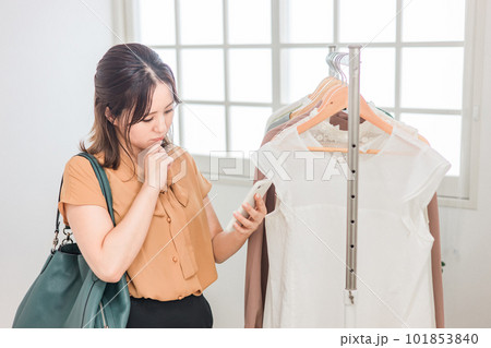 スマホを持ちながら買い物をする女性（ファッション・アパレル・ショッピング） 101853840