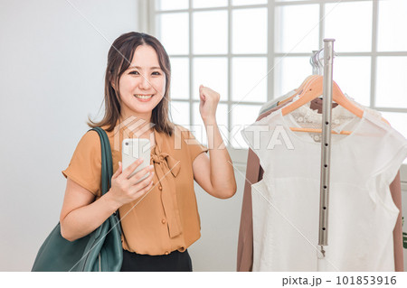 スマホを持ちながら買い物をする女性（ファッション・アパレル・ショッピング） 101853916