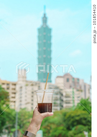 Woman hand holding a glass of ice coffee against Taipei city background 101854410