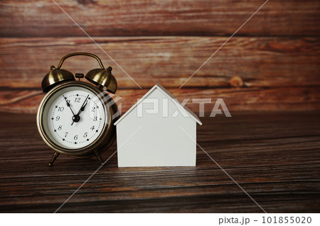 House model with alarm clock on wooden background 101855020