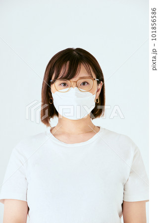 白背景でカメラ目線のマスクと眼鏡を着けた30代の1人の日本人女性の人物の上半身の正面 白背景でカメラ目線のマスクと眼鏡を着けた30代の1人の日本人女性の人物の上半身の正面 101856586