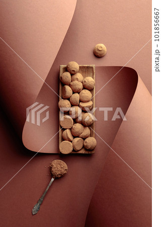 Tasty chocolate truffles and spoon with cocoa powder. 101856667