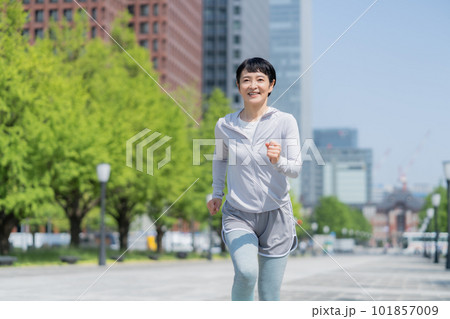 オフィス街の公園でジョギングするミドルエイジの女性 101857009