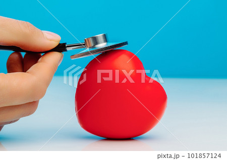 A doctor with stethoscope examining red heart, isolated on blue background A doctor with stethoscope examining red heart, isolated on blue background 101857124