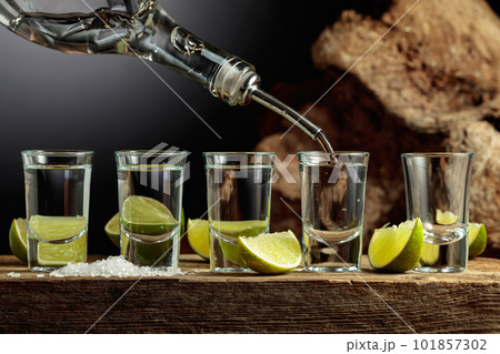 Tequila is poured from a bottle into a glass. 101857302