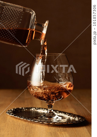 Brandy is poured into a snifter glass. Brandy is poured into a snifter glass. 101857306