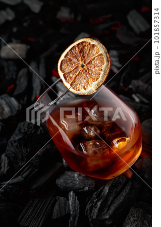 Cocktail with ice and dried orange slice. 101857314