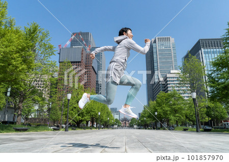 オフィス街の公園でジャンプするミドルエイジの女性 101857970