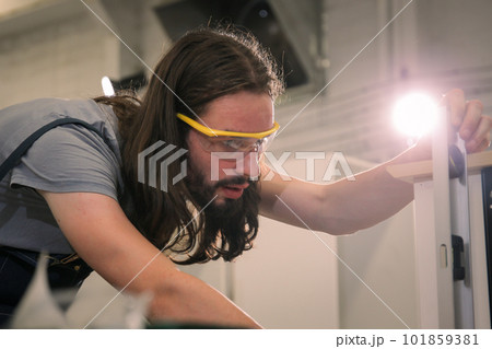 Professional carpenters using a ruler and spirit level to measures a wood panel. Professional carpenter measuring a wood plank. Professional carpenters using a ruler and spirit level to measures a wood panel. Professional carpenter measuring a wood plank. 101859381