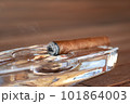 Burning Cuban cigar in a glass ashtray 101864003